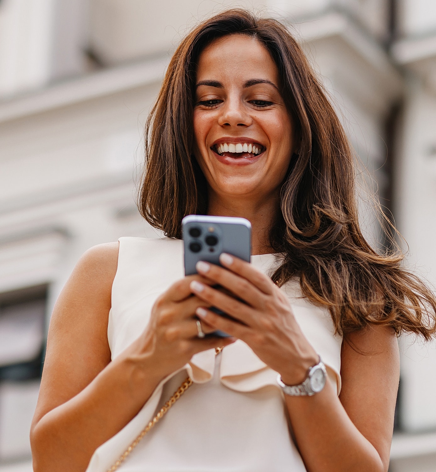 Smiling woman using smartphone outdoors.