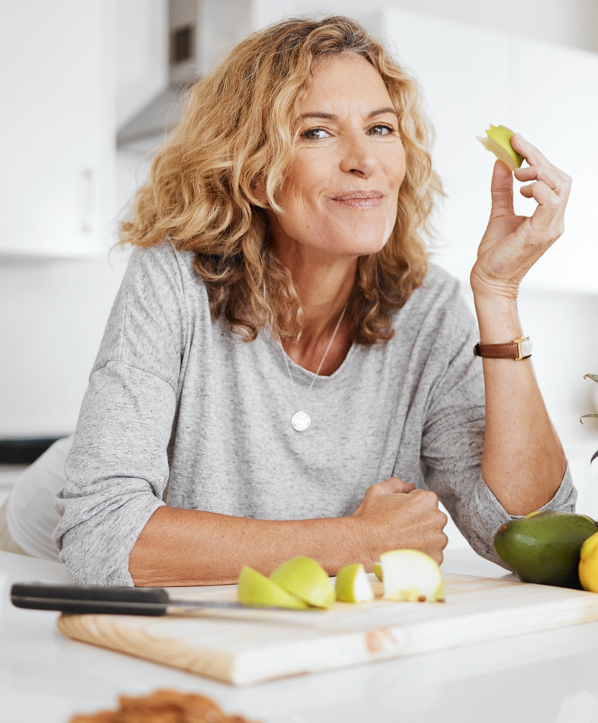 Smiling woman enjoying healthy green apple slice.