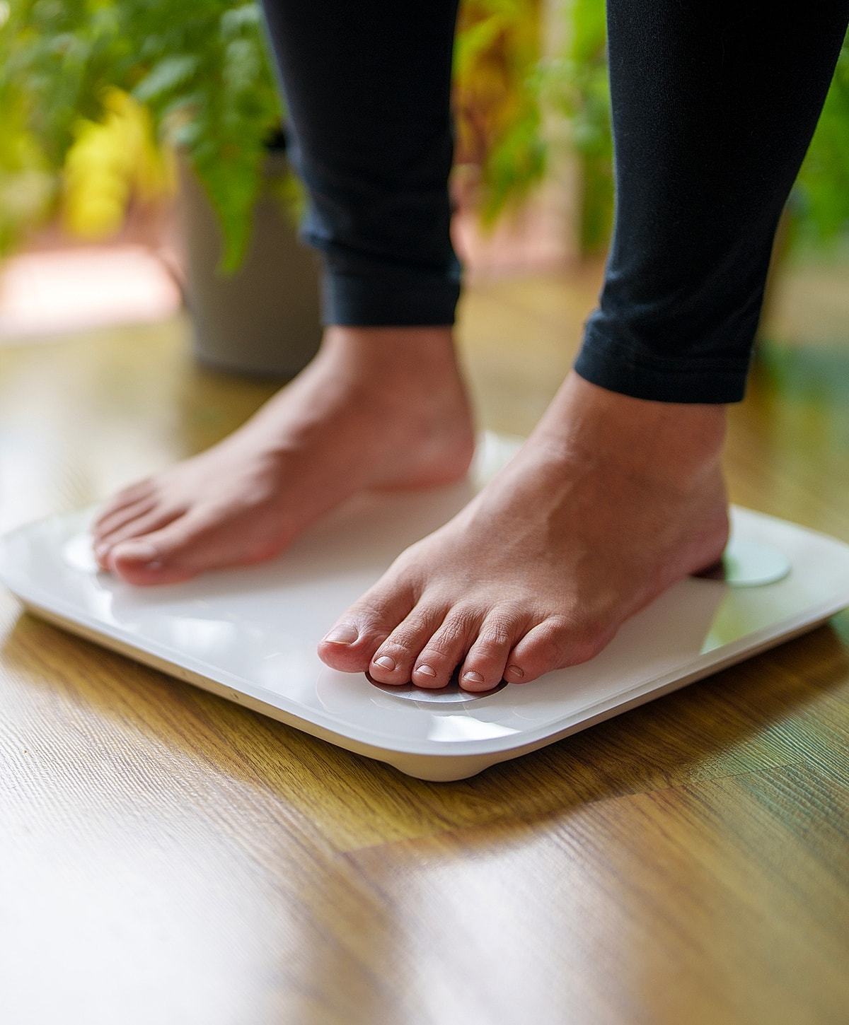 Person weighing themselves on a bathroom scale.