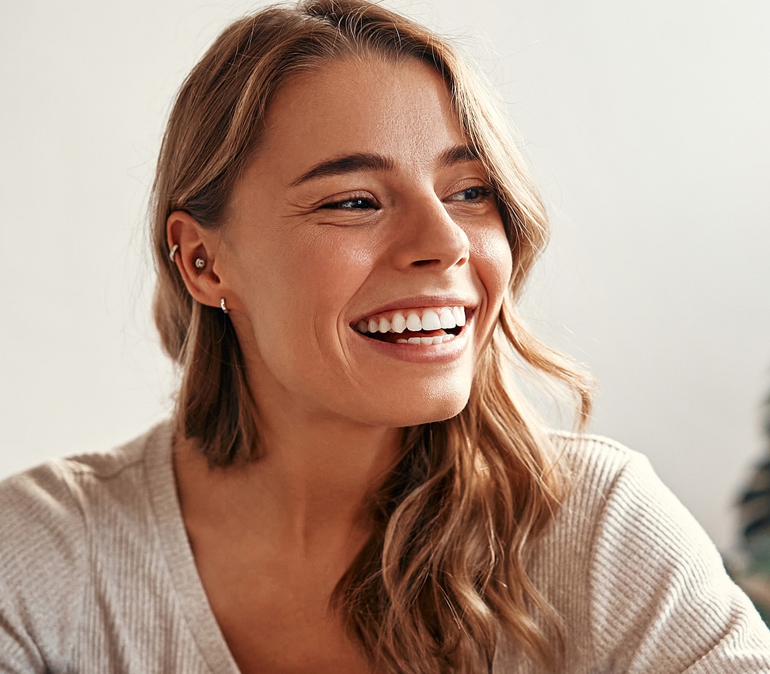 Smiling woman with wavy hair and earrings.