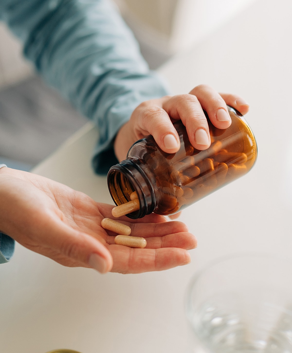 Hand pouring capsules from a bottle.