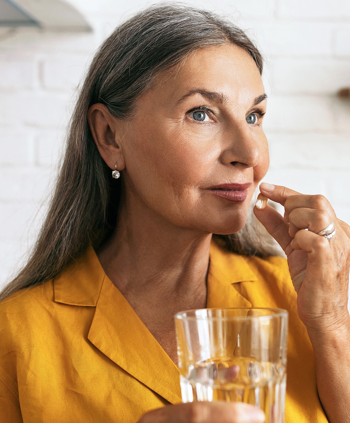Woman taking a supplement with a glass of water.