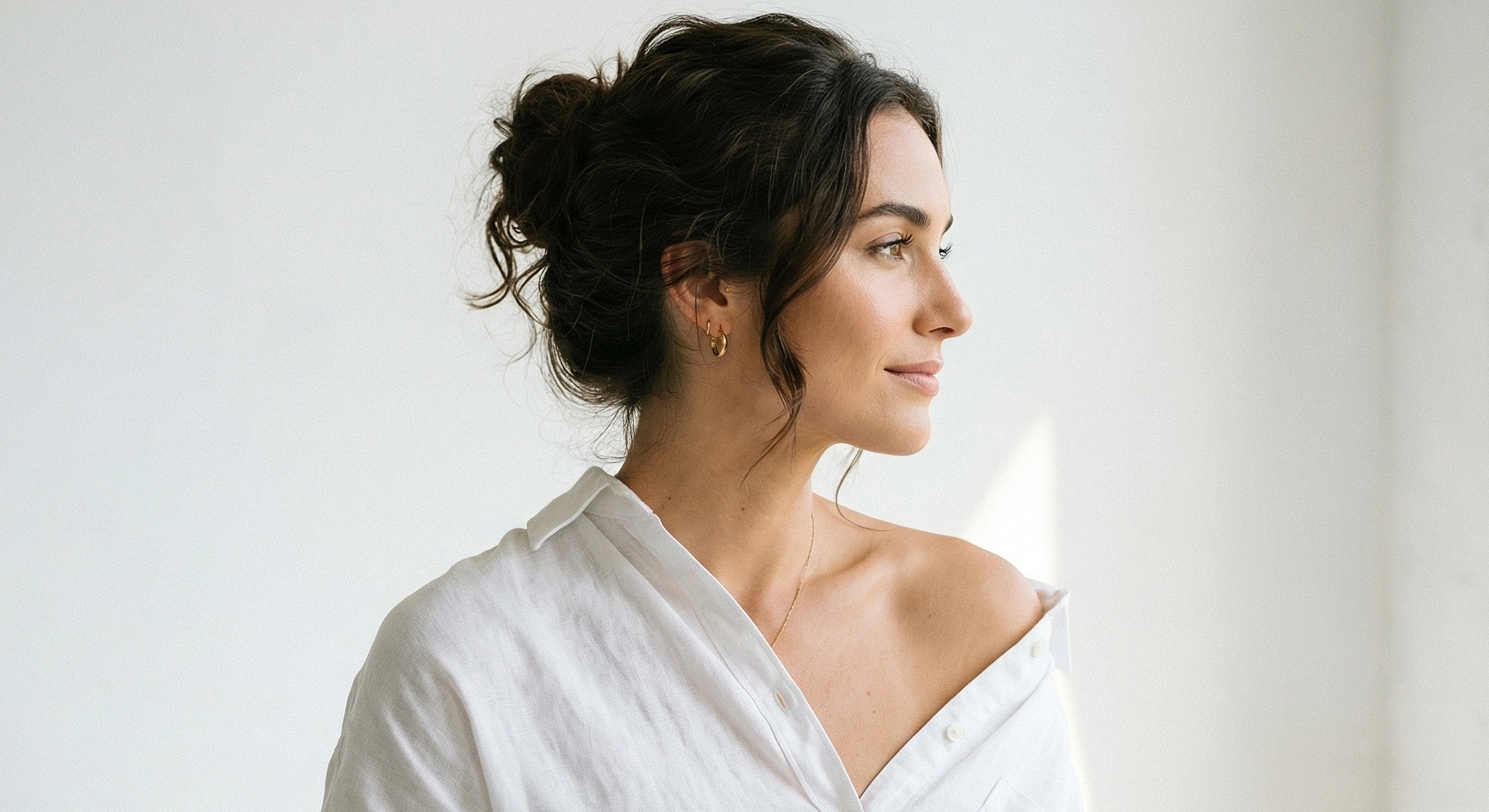 Woman in white shirt looking thoughtfully to the side.