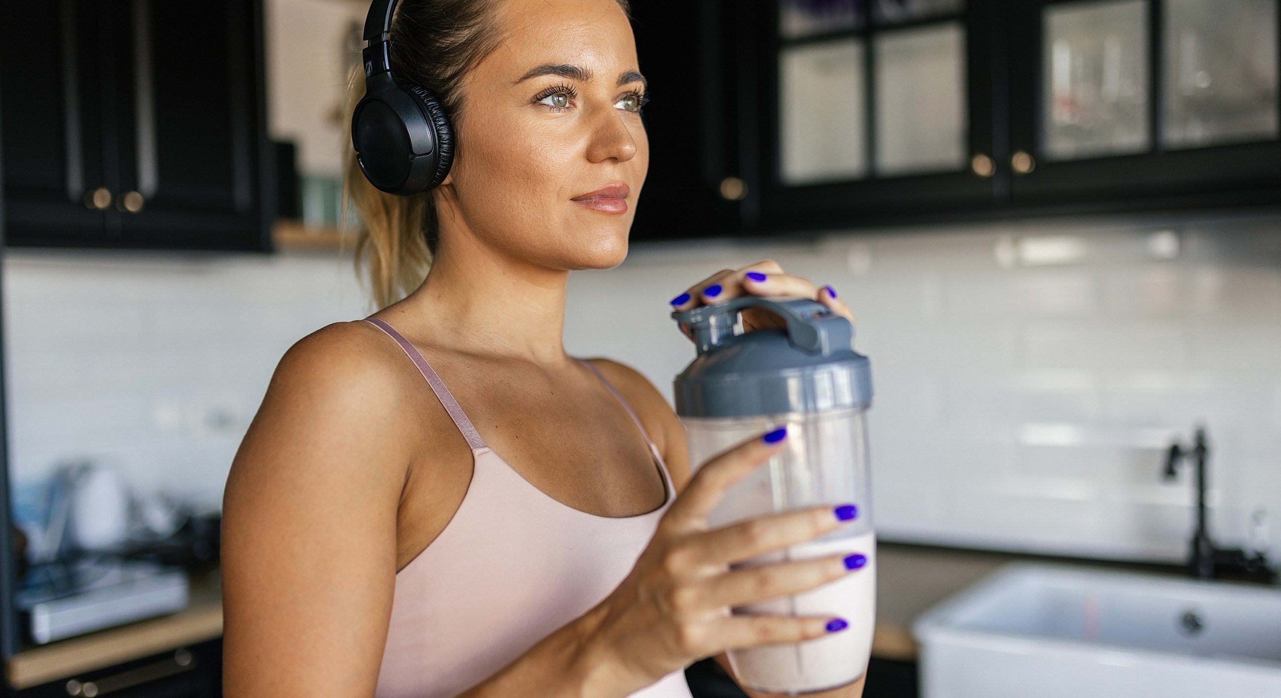 Woman with headphones holding a shaker bottle.