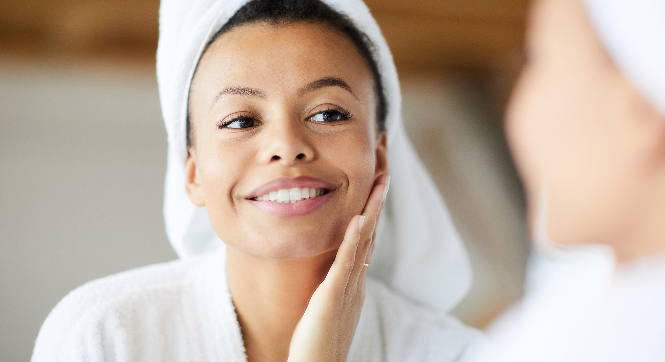 Woman in towel enjoying skincare routine at home.