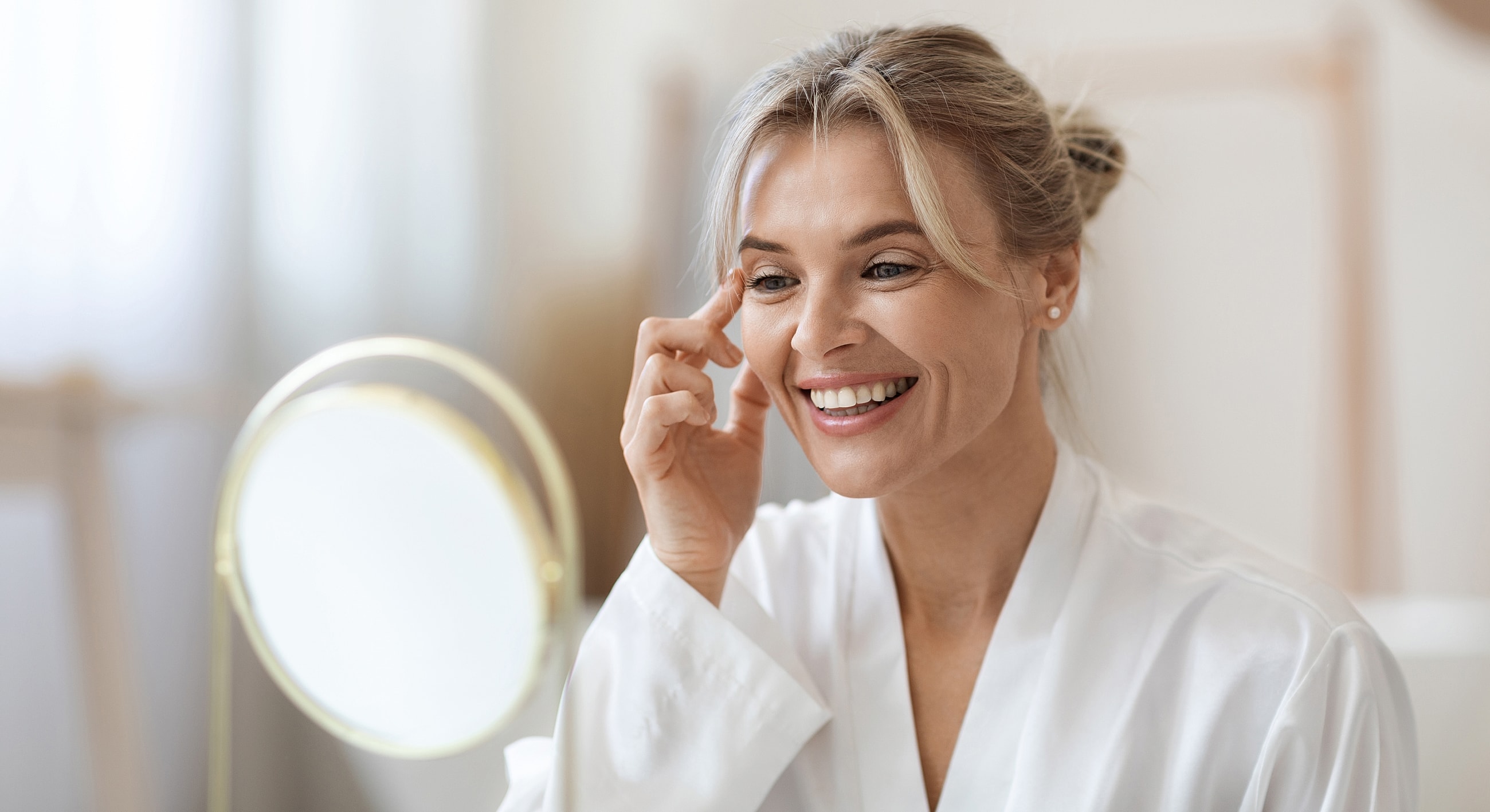 Woman applying skincare in front of mirror.