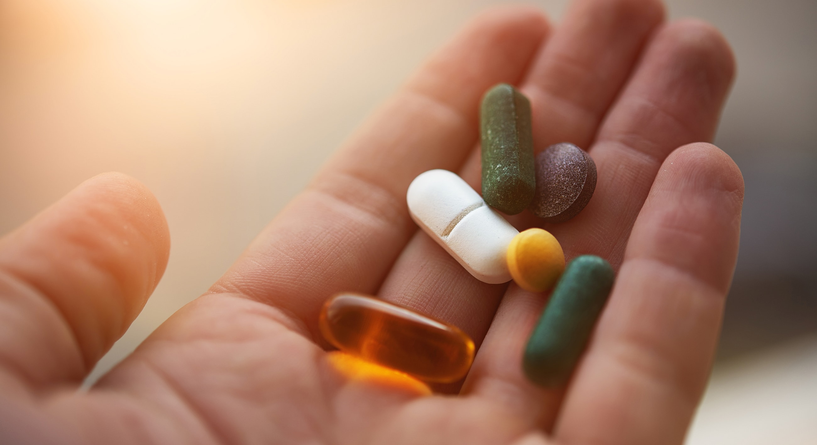 Hand holding various colorful dietary supplements.