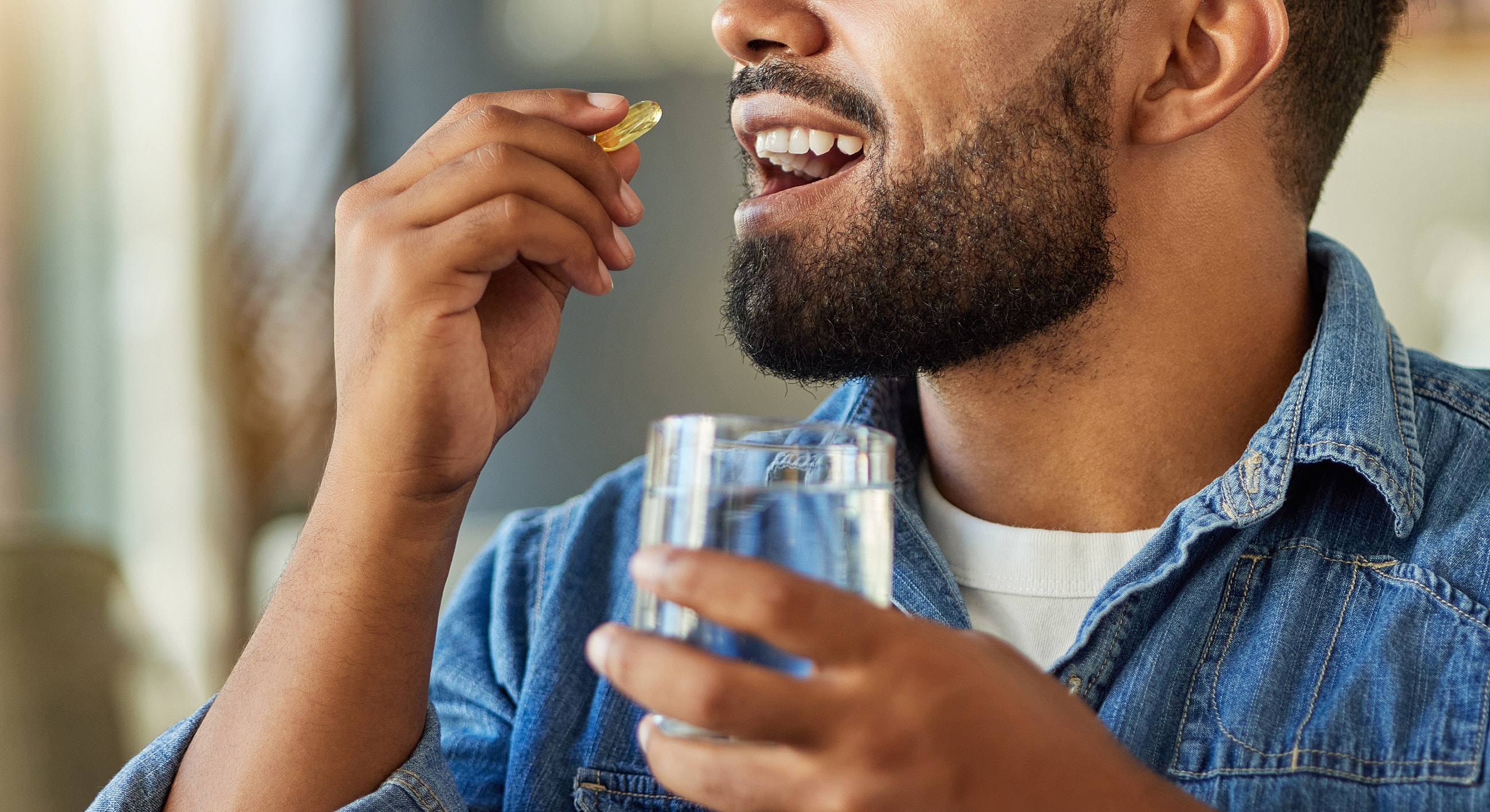 Man taking a supplement with a glass of water.