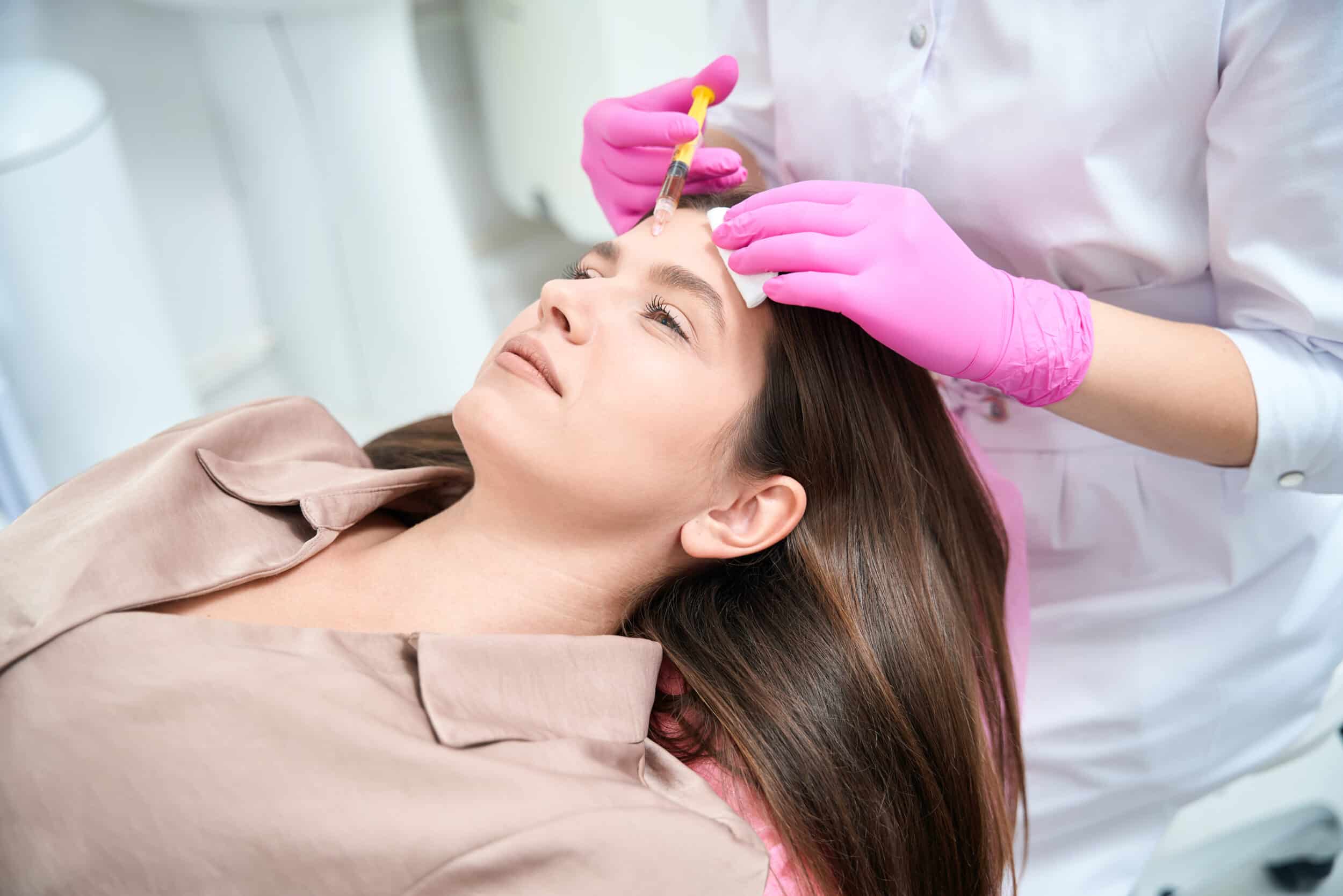 Medical worker on cosmetology procedure with woman