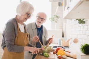 Smiling older couple prepares a healthy meal as part of their Optavia® weight loss plan