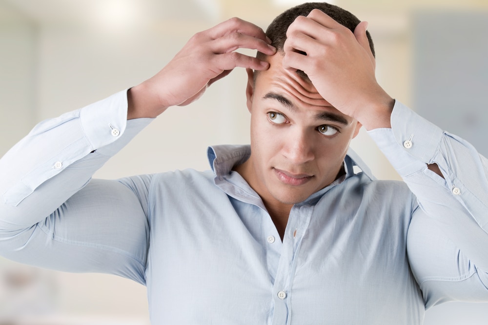 Man looks at his thinning hair in the mirror