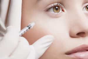 Woman looks up as her injector treats jelly rolls under the eyes with Botox
