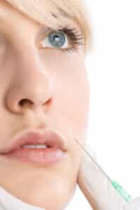 Injector places dermal fillers in a woman's cheek to restore volume after weight loss in Columbia